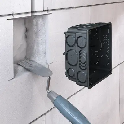 Make an appropriate wall opening, feed the cables and conduits into the housing and fasten it (using plaster) in the wall.